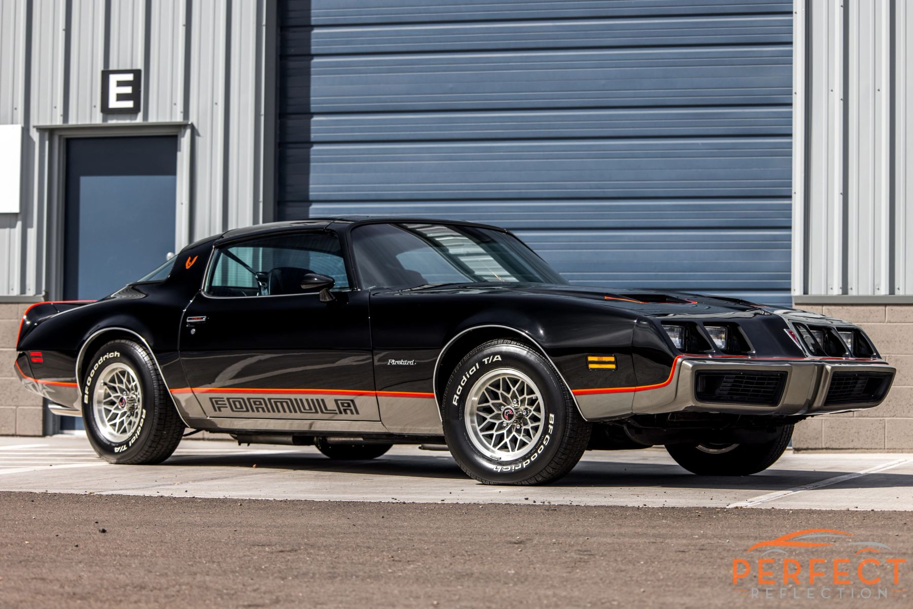 Black Pontiac Trans Am with gold accents parked outside the Perfect Reflection shop