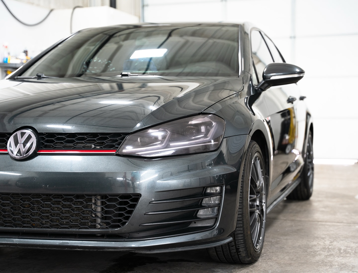 Dark gray Volkswagen GTI with a freshly detailed, glossy finish in the shop