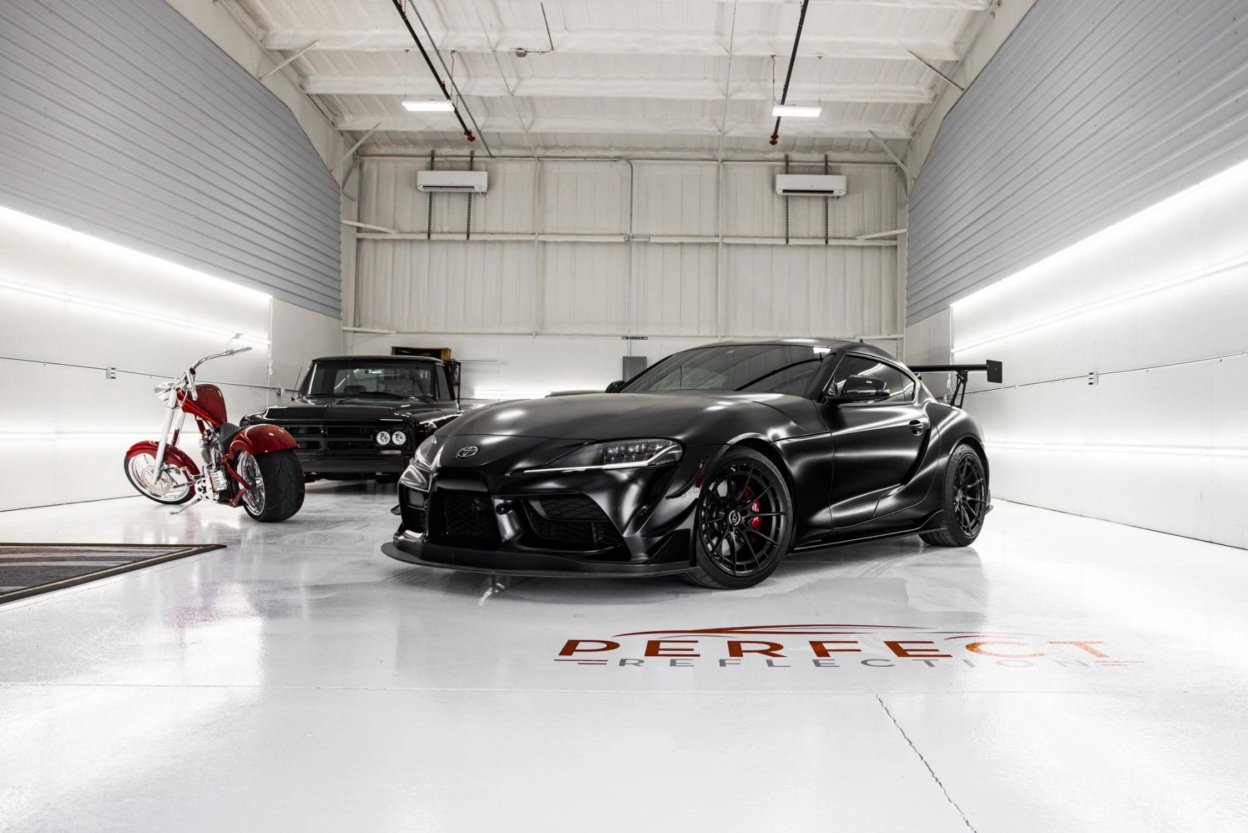 Inside the bright, clean Perfect Reflection shop with a black sports car